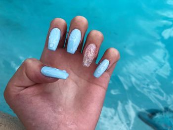 Cropped hand of woman with nail polish by swimming pool