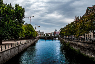 Canal amidst buildings in city against sky