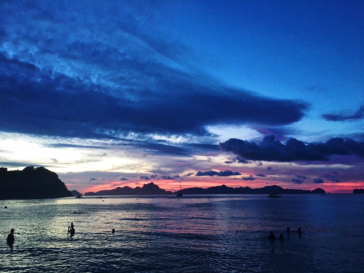 SCENIC VIEW OF SEA AND SILHOUETTE MOUNTAINS AGAINST SKY