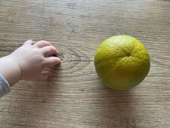 Close-up of hand holding fruit on table