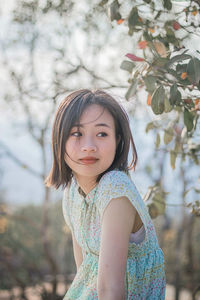 Portrait of woman standing against tree