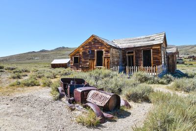 Abandoned built structure on field against clear blue sky