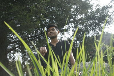 Young man standing amidst trees in forest