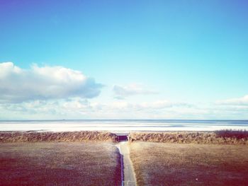 Scenic view of road by sea against sky