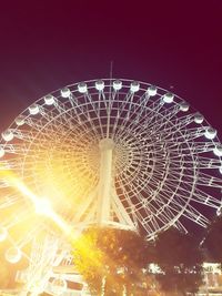 Low angle view of illuminated ferris wheel against sky at night