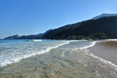 Scenic view of beach against clear blue sky