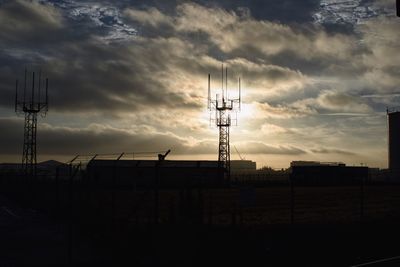 Silhouette of electricity pylon against sky during sunset