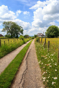 Road amidst field against sky