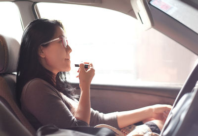 Woman applying lipstick in car