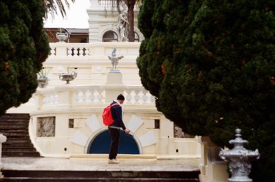 Side view of man standing by building against trees