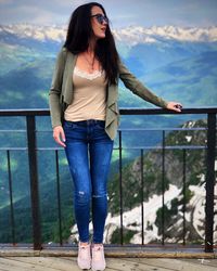Full length of woman standing on railing against mountains
