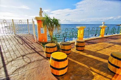 Chairs and table on beach by sea against sky