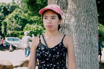 Portrait of teenage girl standing against tree trunk