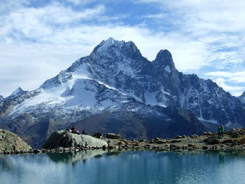 Scenic view of lake by snowcapped mountains against sky