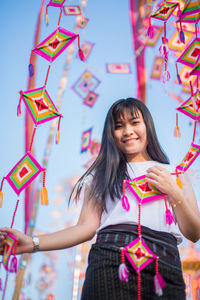 Portrait of smiling woman holding colorful decorations