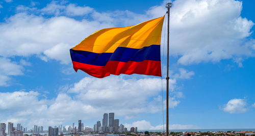 Low angle view of flag against buildings in city against sky