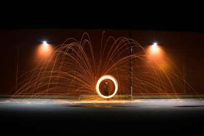 Man spinning wire wool on road at night