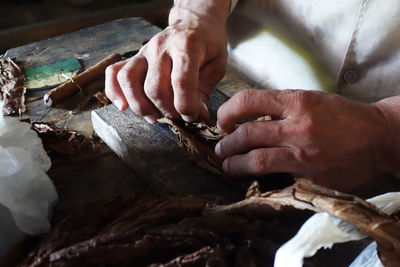 Midsection of man making cigar 