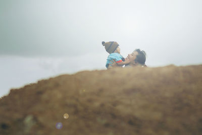 Low angle view of mother and daughter against sky