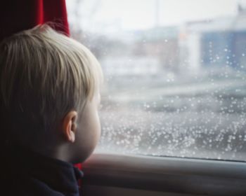 Rear view of boy looking through window