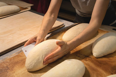 Close-up of female hands kneading dough for making artisan bread at home bakery