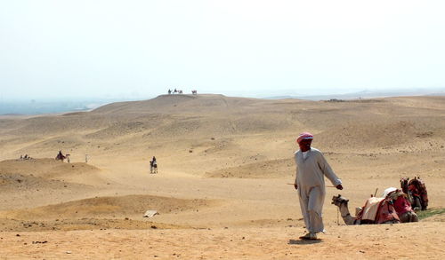 People standing on desert against clear sky