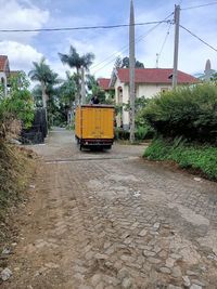 Cars on road by buildings against sky