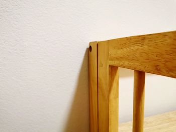 Close-up of wooden table against wall