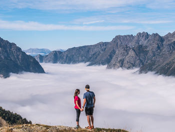 Rear view of friends on mountain against sky