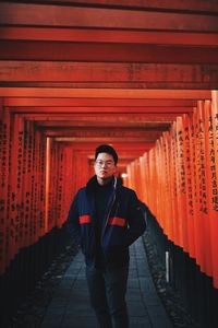 Full length portrait of young man standing in temple outside building