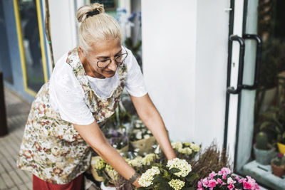 Blond female florist arranging flowers outside store