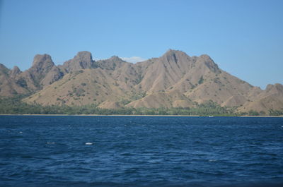 Scenic view of sea and mountains against clear blue sky