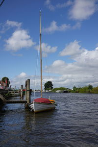 Sailboats moored in sea against sky