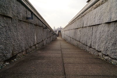 Walkway amidst buildings against sky