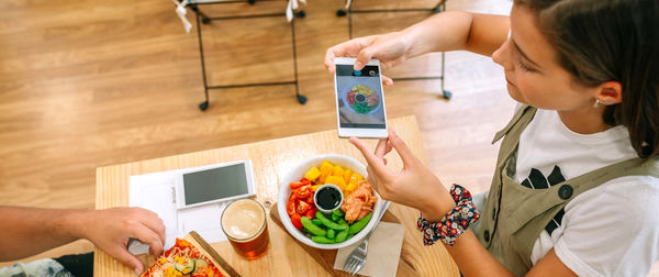 Midsection of woman using mobile phone on table