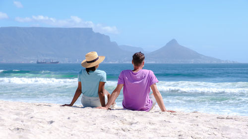 Rear view of woman standing at beach against sky