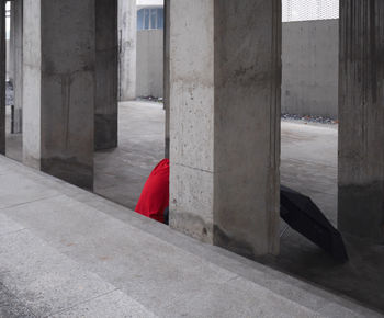 Rear view of man hiding by column on street