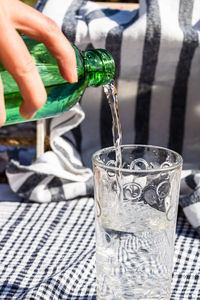 Midsection of person pouring drink in glass on table