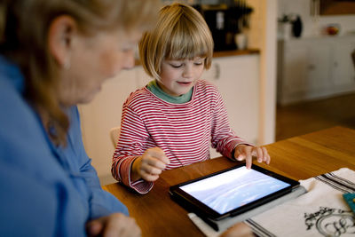 Grandmother looking at grandson using digital tablet