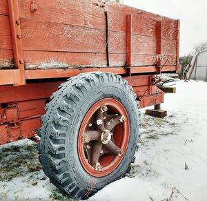 Cropped image of old red trailer on field at farm during winter