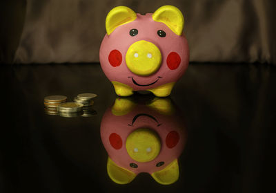 Close-up of coins and piggy bank on table