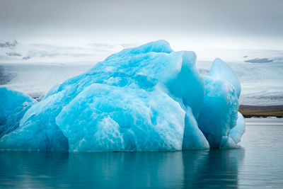 Ice floating on water in winter against sky