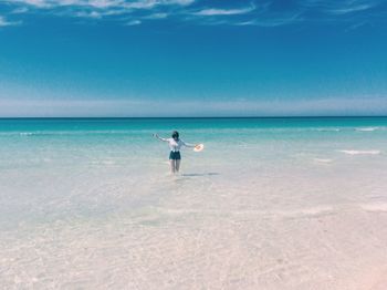 Woman standing in sea against sky