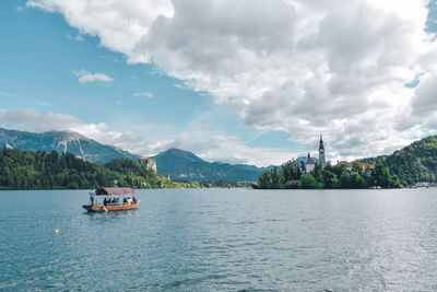 Scenic view of boats in lake against cloudy sky