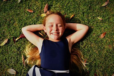 Directly above shot of happy girl lying down on grassy field