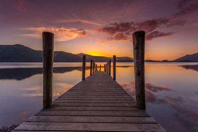 Pier over lake against sky during sunset