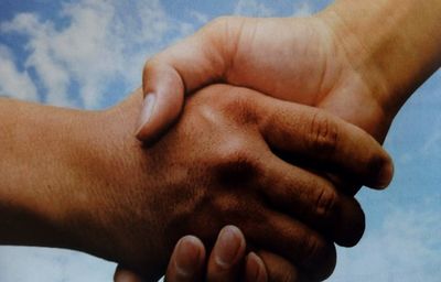 Close-up of man holding hands against sky