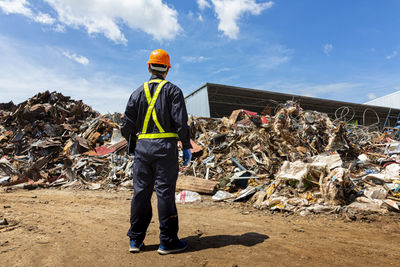 Full length of man standing by garbage against sky