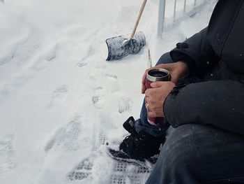 Low section of man holding snow on field