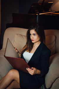 Young woman sitting on sofa at home